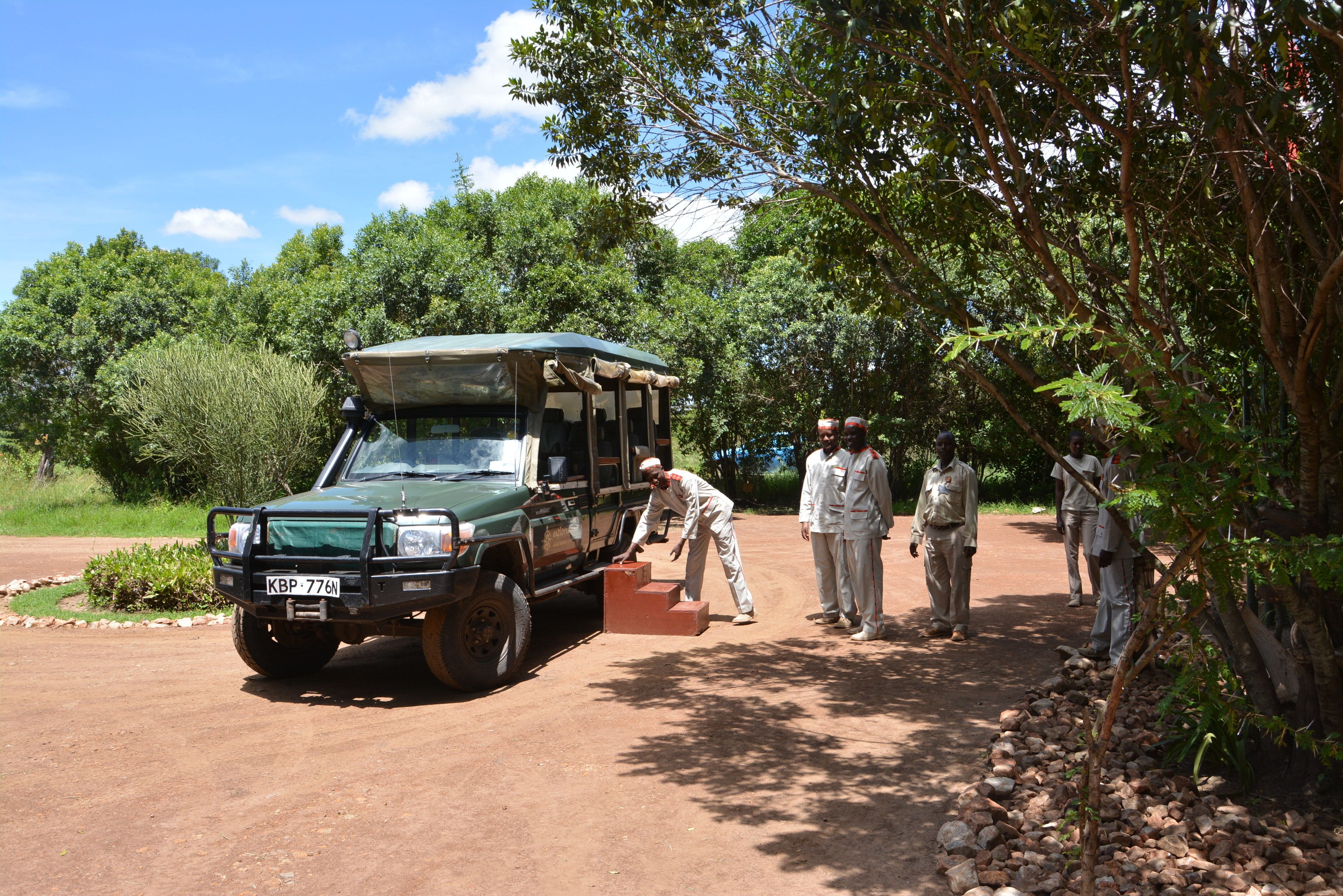 Un vehículo safari estacionado en un camino de tierra con gente cerca.