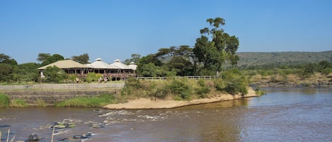 Un hotel a la orilla del río con terraza al aire libre y vistas del río.