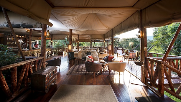 Un'area lounge con tende, pavimento in legno, posti a sedere e un bar.