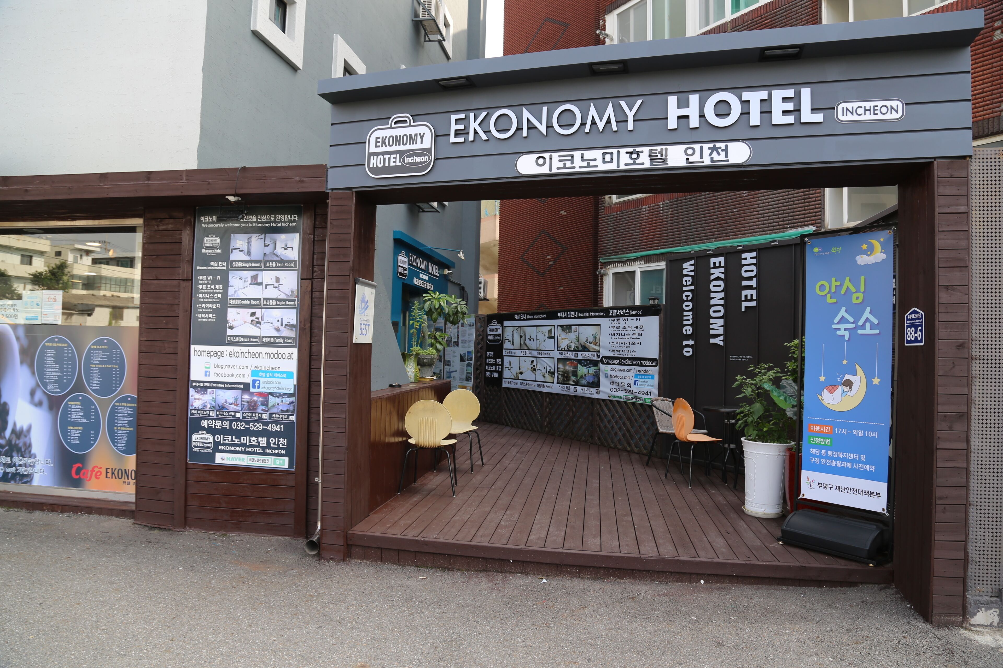The exterior of the Economy Hotel in Incheon, featuring a wooden entrance, a reception desk, and various informational posters.