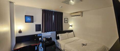 Une chambre d’hôtel équipée d’un lit, d’un bureau et d’une chaise, d’un téléviseur à écran plat, d’un climatiseur et d’un panneau indiquant la présence d’une connexion Wi-Fi.