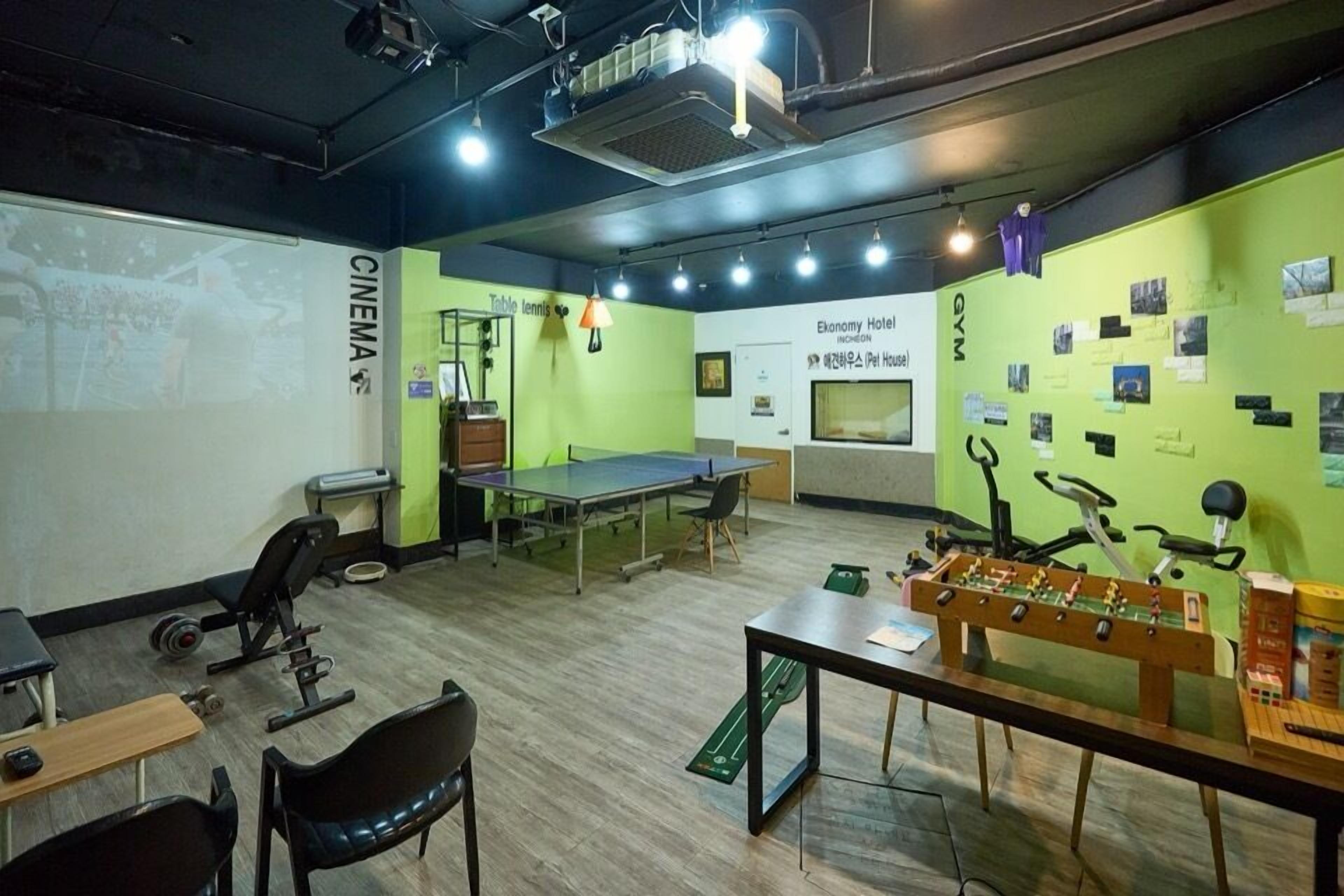 A multifunctional room with a ping pong table, foosball table, and exercise equipment.
