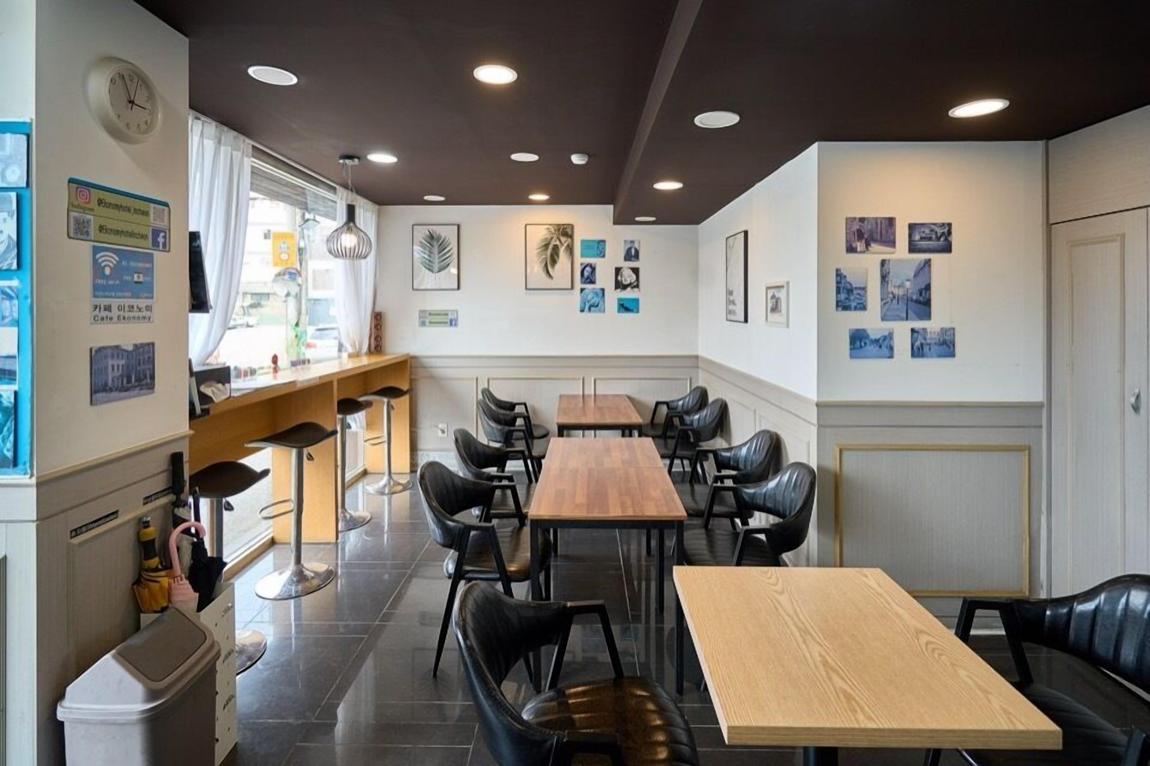 Un restaurante con una larga mesa de madera, sillas de cuero negro y una zona de bar con taburetes.
