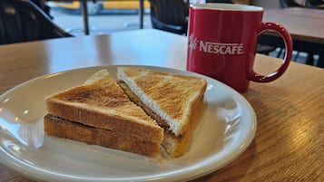 Une assiette avec un sandwich et une tasse rouge sur une table en bois.
