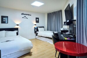 Una habitación de hotel con dos camas, un escritorio con computadora, un televisor y una silla roja.