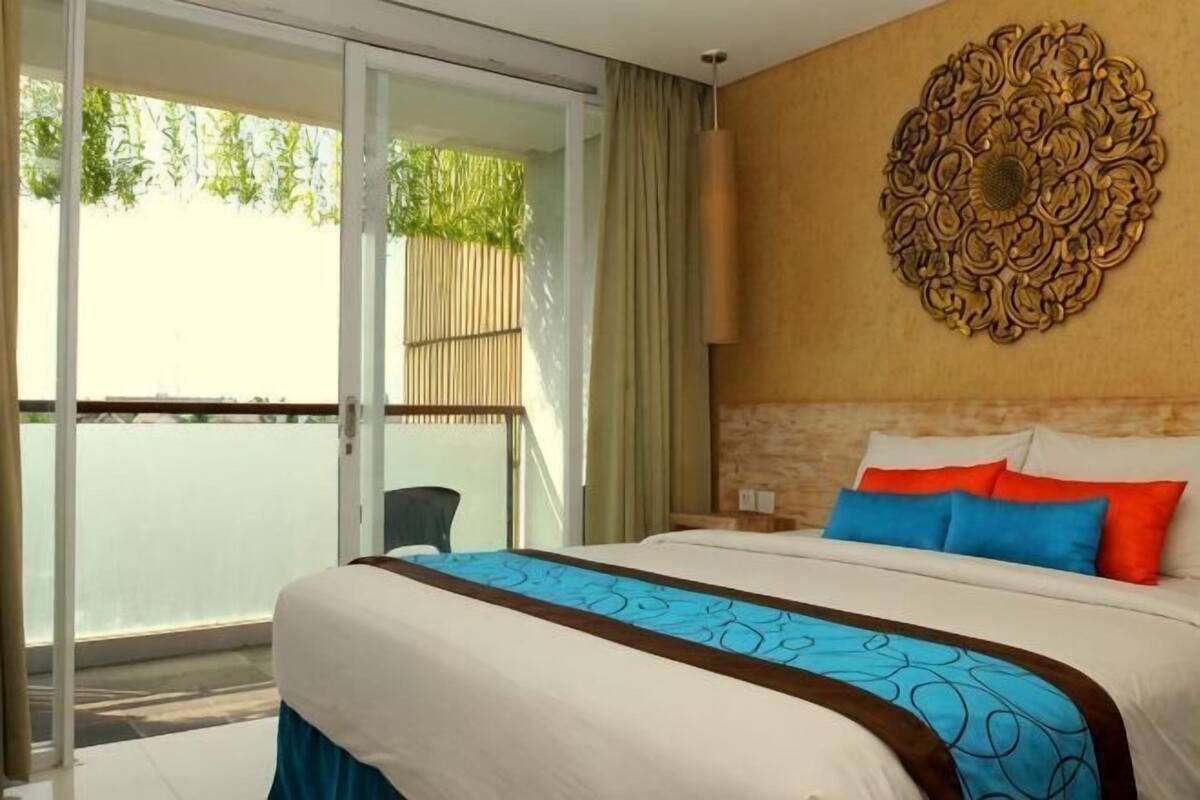 Ein Hotelzimmer mit Bett, einer großen Wanddekoration und einer Glastür zum Balkon.
