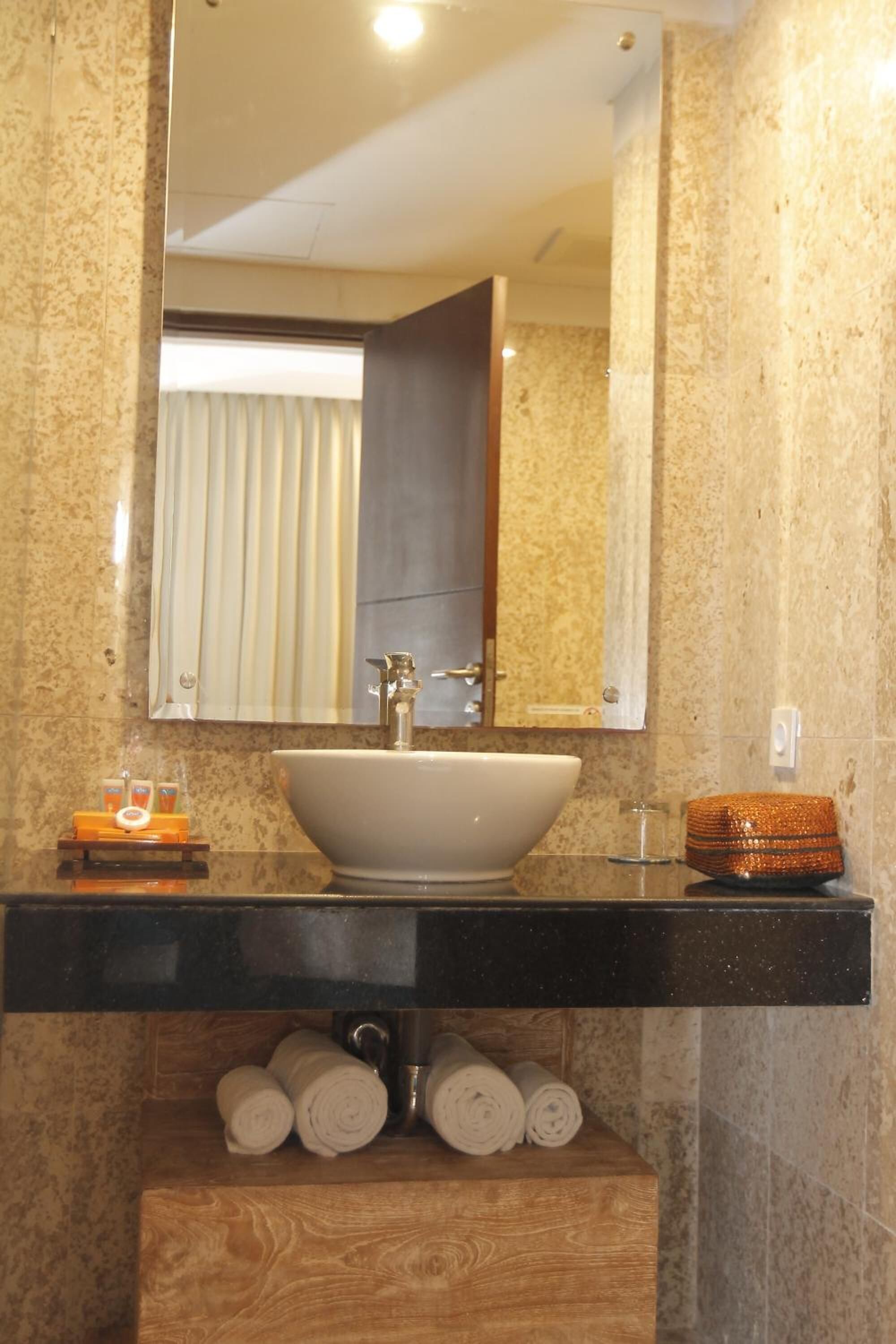 A bathroom with a large oval sink, a mirror above it, and a wooden vanity below.