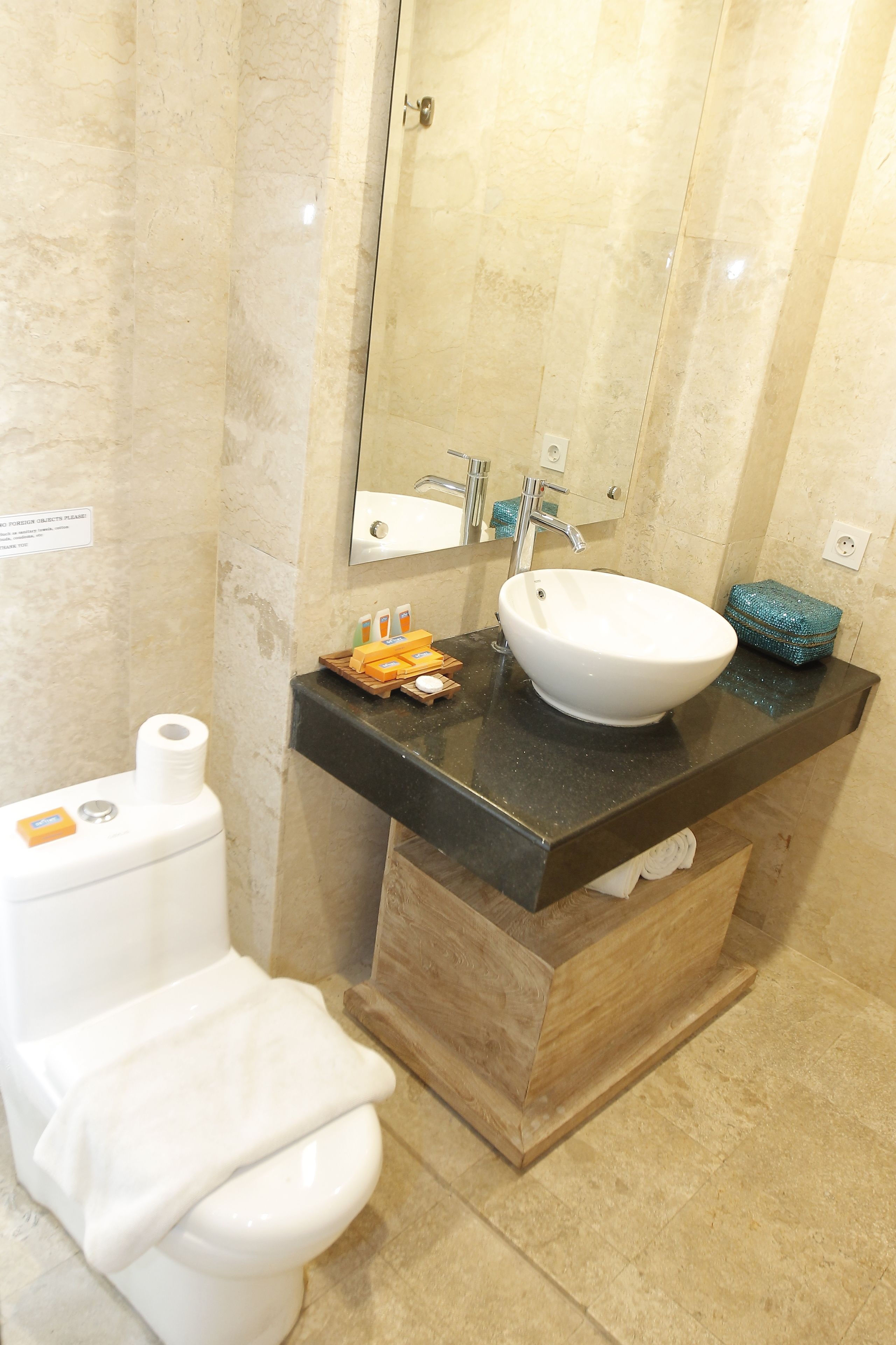A bathroom with a white toilet, a sink with a mirror above it, and a wooden cabinet below.