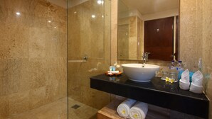 A modern bathroom with a glass-enclosed shower, a white sink, and a wooden vanity. - Destiny Boutique Hotel (Seminyak)
