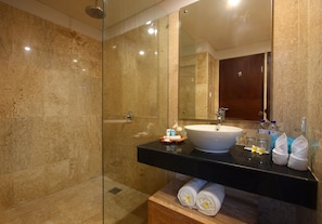 A modern bathroom with a glass-enclosed shower, a white sink, and a wooden vanity. - Destiny Boutique Hotel (Seminyak)