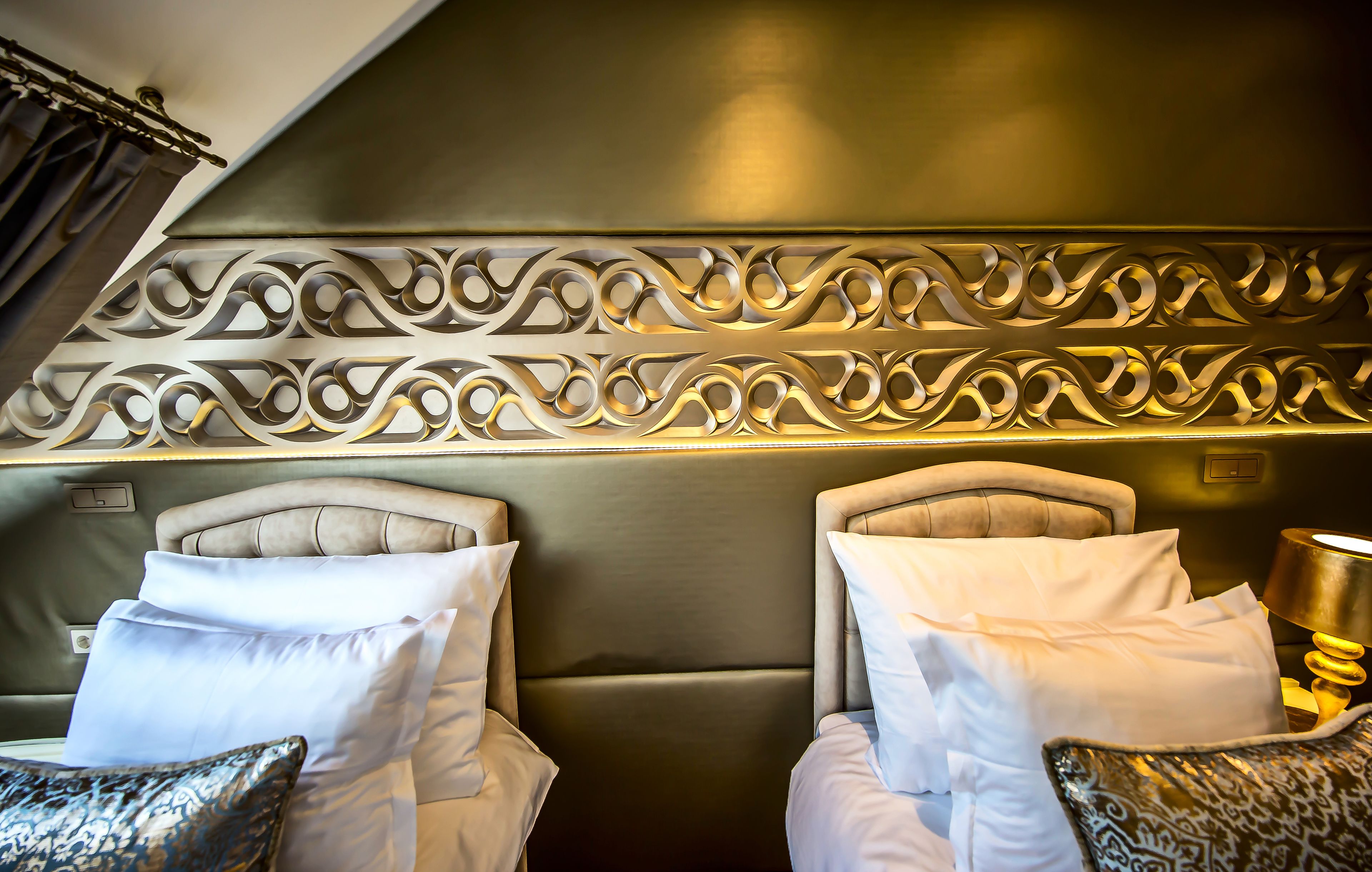 A hotel room with two beds, each with a headboard and pillows.