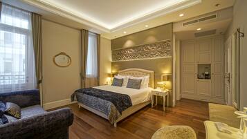 Une chambre spacieuse avec un grand lit, un coin salon avec un fauteuil et une armoire.