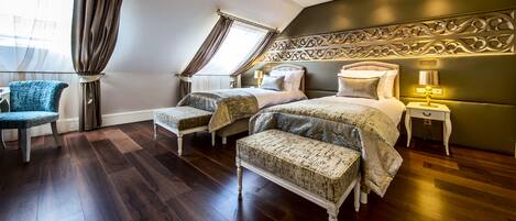 A bedroom with a large bed, two bedside tables, a chair, and a bench.