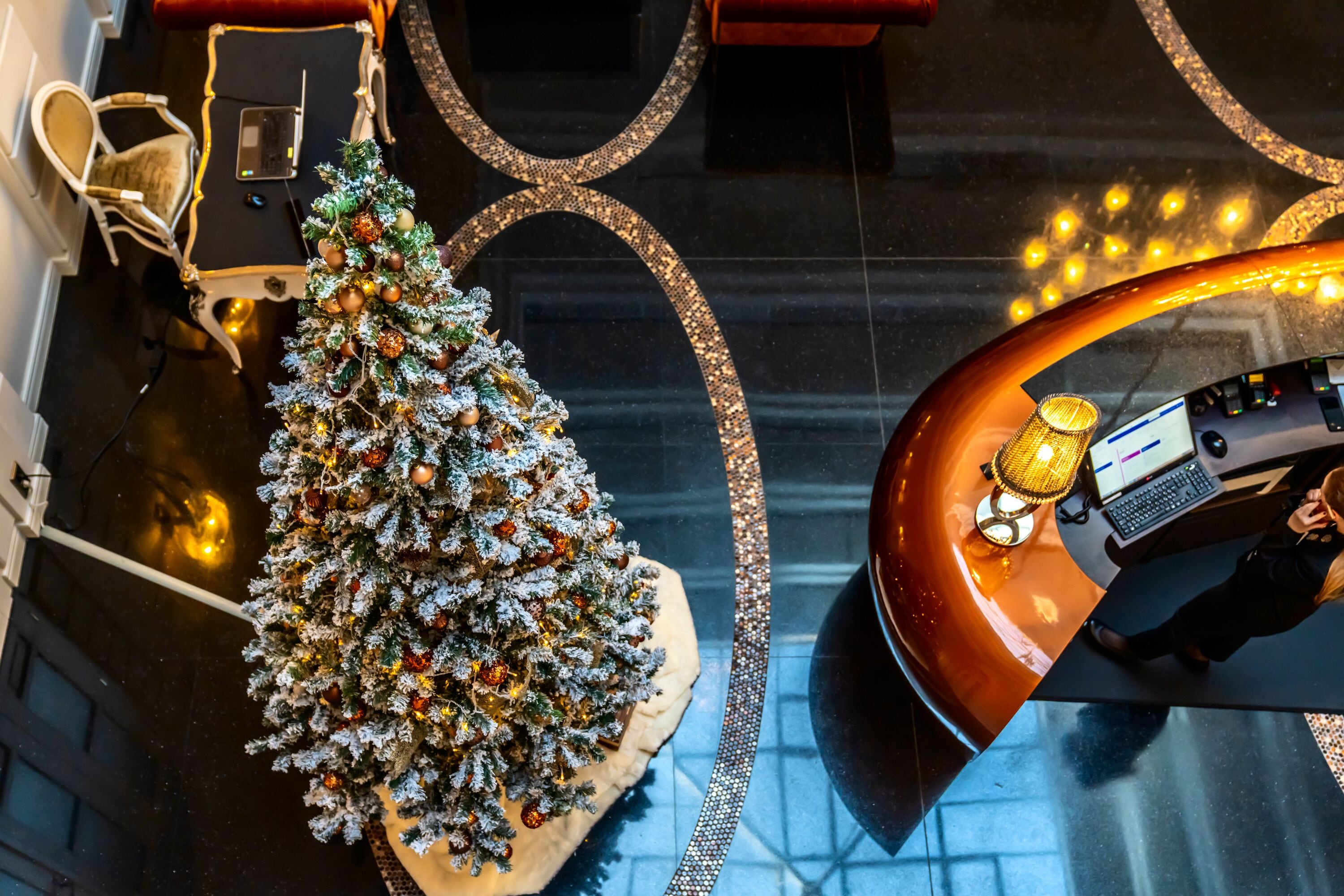 Un sapin de Noël dans un hall d’entrée, avec un comptoir d’accueil incurvé et une chaise.