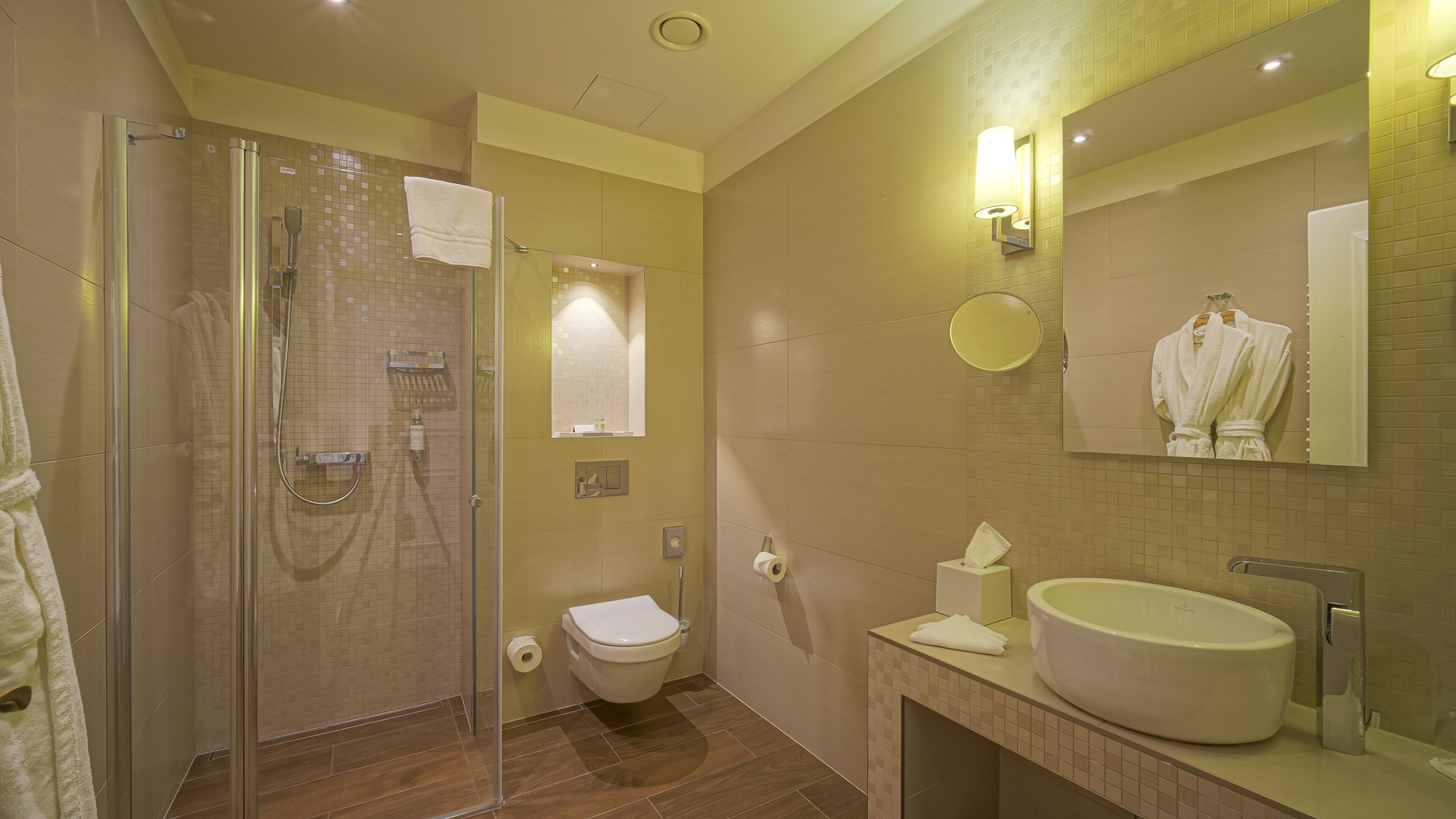 A modern bathroom with a glass shower enclosure, a toilet, and a sink with a mirror above it.