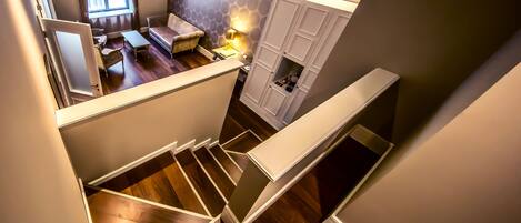 Un escalier menant à un espace de vie comprenant un canapé, une table et une lampe.