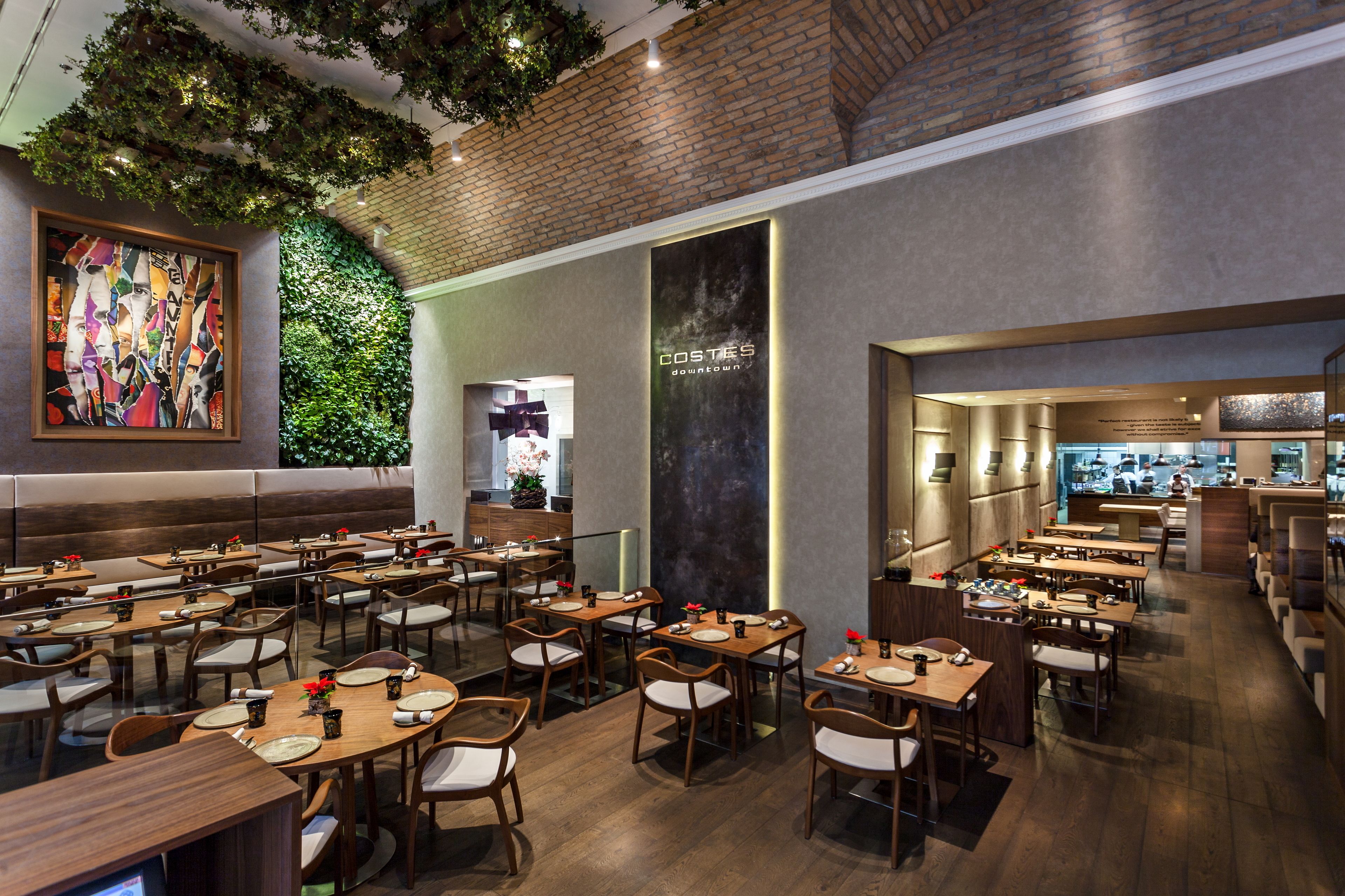 A restaurant with multiple dining tables and booths, a brick wall, and a large mural.