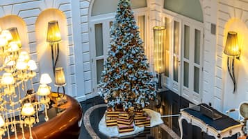 En imponerende lobby med et stort juletræ, elegante lysekroner og en luksuriøs receptionsdisk.