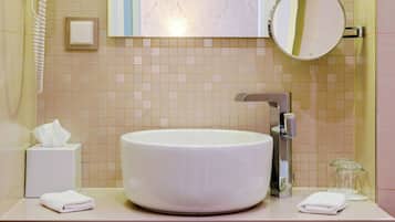 Un baño con un lavamanos grande de color blanco, un espejo, un dispensador de toallas y un teléfono.
