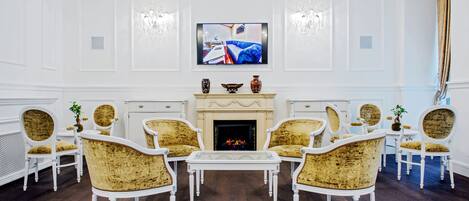 Una habitación con chimenea, muebles blancos y un televisor montado encima.