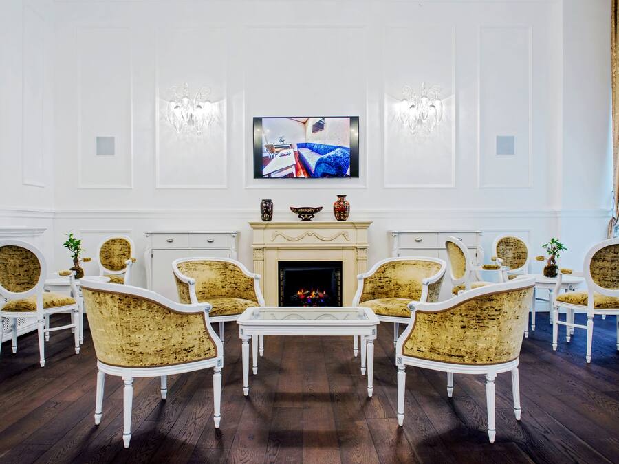 Una habitación con chimenea, muebles blancos y un televisor montado encima.