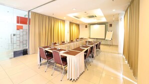 A conference room with a long table, chairs, a projector screen, and curtains. - Amaris Hotel Bekasi Barat (Bekasi)