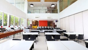 A modern dining area with high ceilings, large windows, and a mezzanine level. - Amaris Hotel Bekasi Barat (Bekasi)
