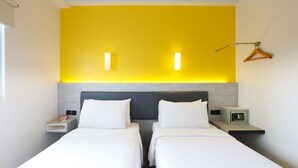 A hotel room with two beds, a bedside table with a lamp, a wall-mounted light, and a coat hanger. - Amaris Hotel Bekasi Barat (Bekasi)