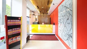 A reception area with a wooden ceiling, a bright yellow counter, and a red wall with a map. - Amaris Hotel Bekasi Barat (Bekasi)