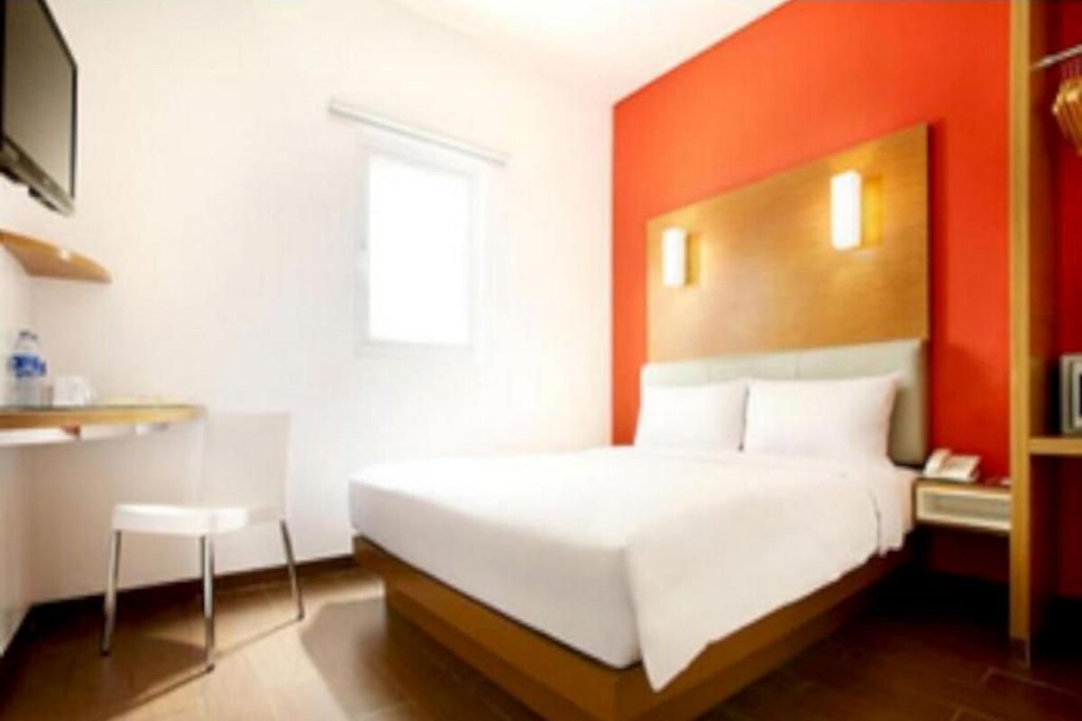 Una habitación de hotel con cama, escritorio, silla y televisión.