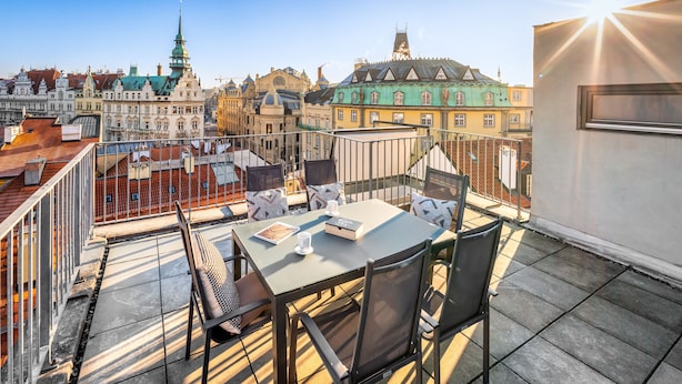 A rooftop terrace with a table and chairs, overlooking a cityscape with historic buildings. - 4 Arts Apartments by Adrez Living (Prague)