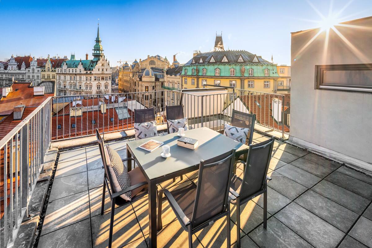 Une terrasse sur le toit, avec une table et des chaises, offrant une vue sur le paysage urbain et ses bâtiments historiques.