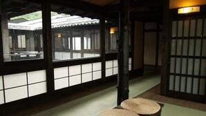 A traditional Japanese room with tatami mats, a low table with woven mats, and sliding doors with frosted glass panels. - Okada Ryokan Warakutei (Takayama)