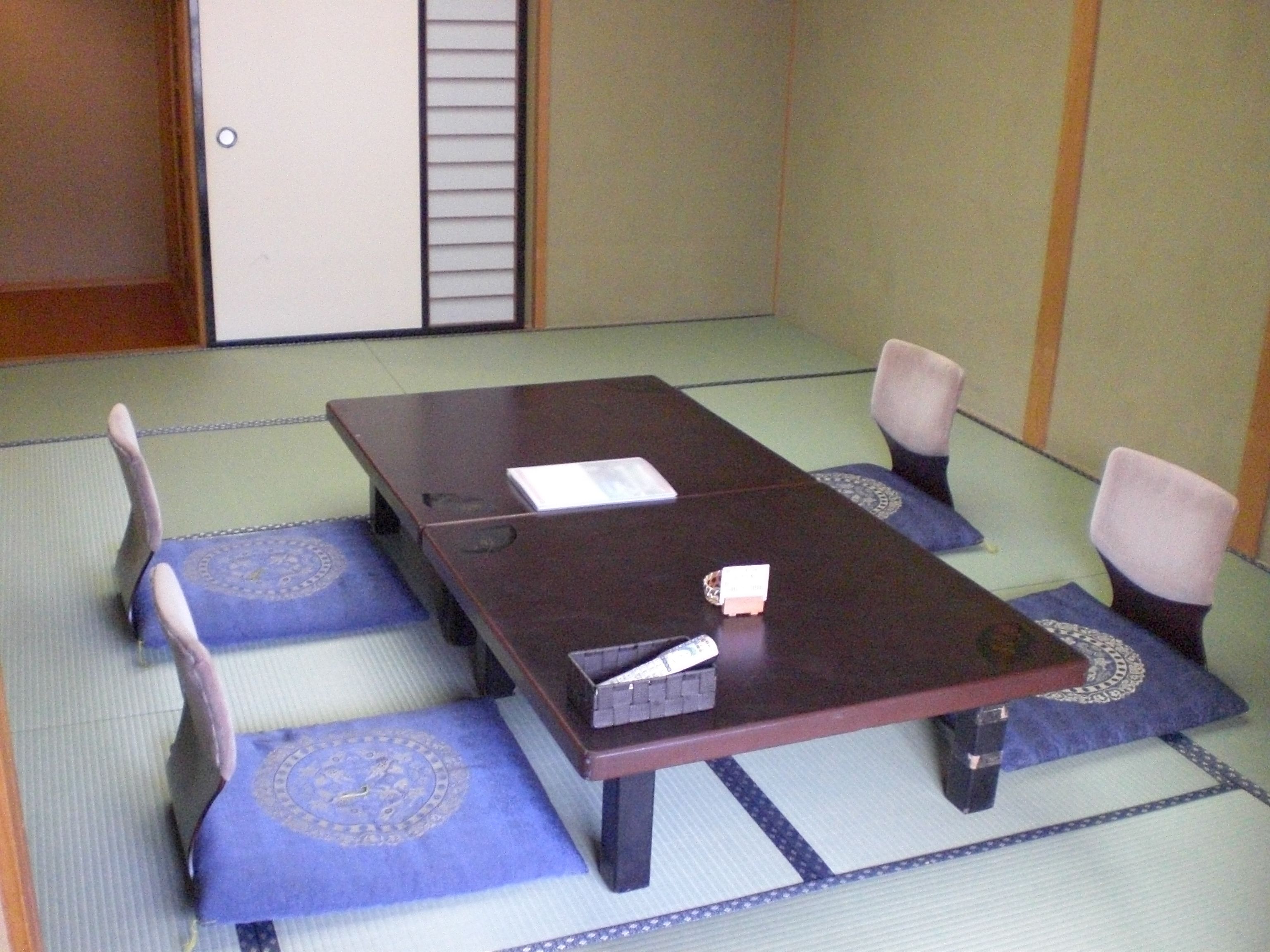 A tatami mat room with a low table and four chairs.