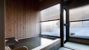 A traditional Japanese onsen with wooden walls and a stone bathtub. - Okada Ryokan Warakutei (Takayama)
