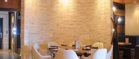 Una sala de conferencias moderna con una mesa redonda, sillas blancas y suelo de madera.