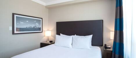 A hotel room with a large bed, a nightstand with a lamp, a framed picture on the wall, and a telephone.