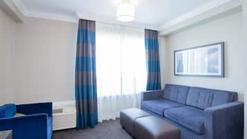 A modern living room with a grey sofa, a blue armchair, and a large window with striped curtains.