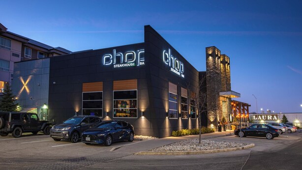 A steakhouse with a modern exterior and a parking lot with several cars.