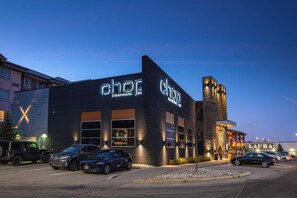 A steakhouse with a modern exterior and a parking lot with several cars. - Sandman Hotel Oakville (Oakville)