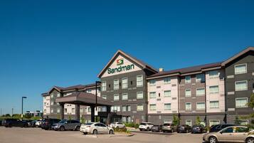 A Sandman hotel with a parking lot and multiple cars.