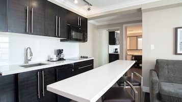 A modern kitchen with dark cabinetry, a white countertop, and a built-in microwave.
