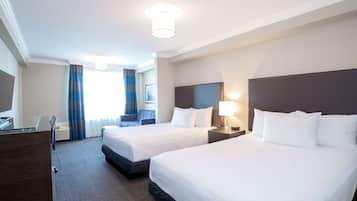 A hotel room with two beds, a desk, and a TV.