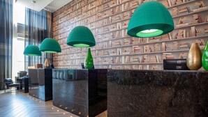 A reception area with a marble counter, green pendant lights, and a bookshelf wall.
