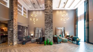 A spacious lobby with a high ceiling, stone pillars, and modern lighting fixtures.