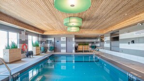An indoor swimming pool with wooden ceiling, clear water, and a lifebuoy.