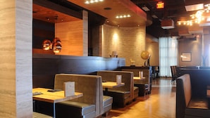 A restaurant interior with booths, tables, and a brick wall.