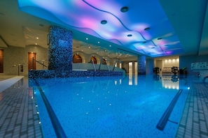 A large indoor swimming pool with a modern design, featuring a mosaic wall and a ceiling with a wave-like pattern. - Pleiada Boutique Hotel And Spa (Iasi)