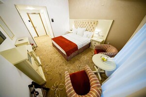 Una habitación de hotel con una cama grande, un escritorio pequeño, una silla y una ventana.