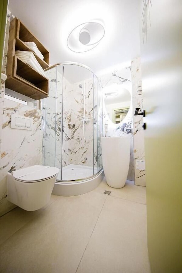 A bathroom with a glass-enclosed shower, a toilet, and a sink.